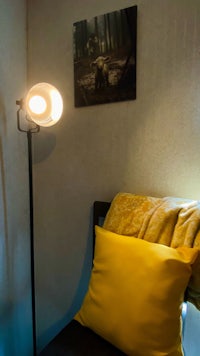 a yellow pillow is on a chair next to a lamp